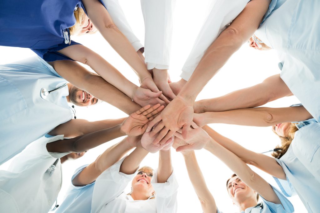 Medical team stacking hands over white background